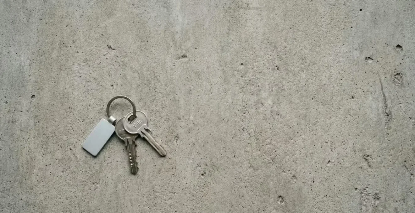 Clés d'appartement posées sur une surface en béton brut symbolisant la perte de valeur du neuf vers l'ancien